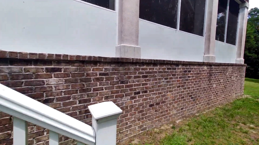Clean red brick foundation and white siding after a house wash
